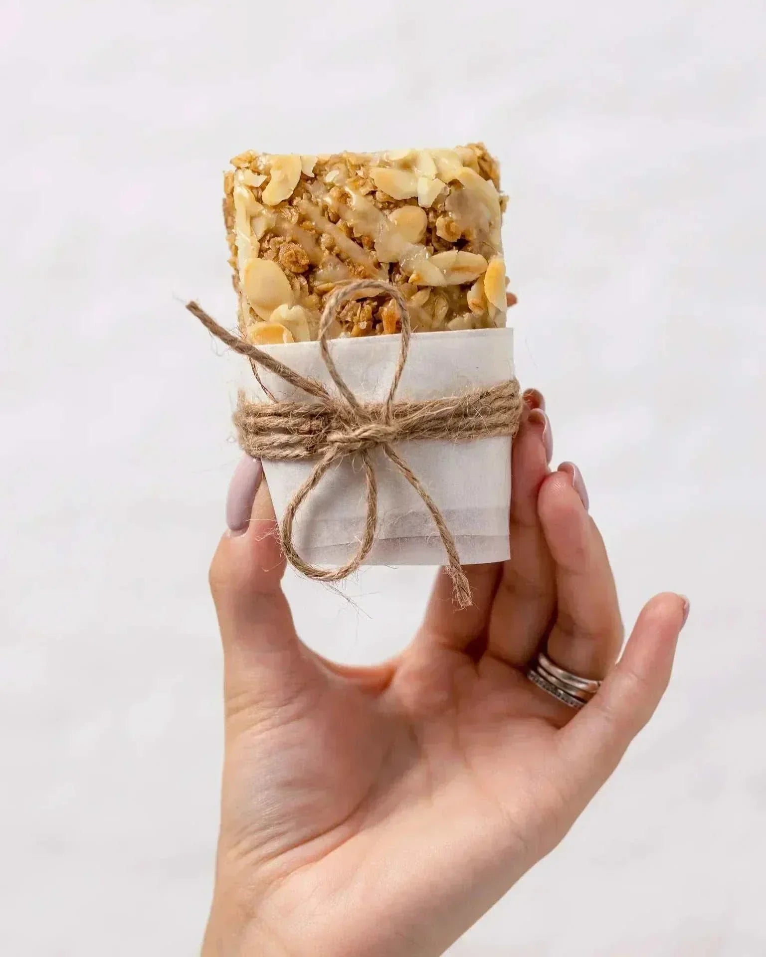 Hand holding a wrapped oat-based flapjack from the Best Sellers Box featuring plant-based, caramelised flapjacks with nuts.
