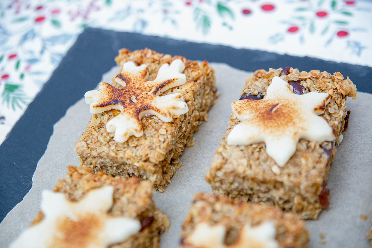 A festive flapjack on a white plate, rich with oats and mincemeat, topped with marzipan, ideal for holiday gifting.