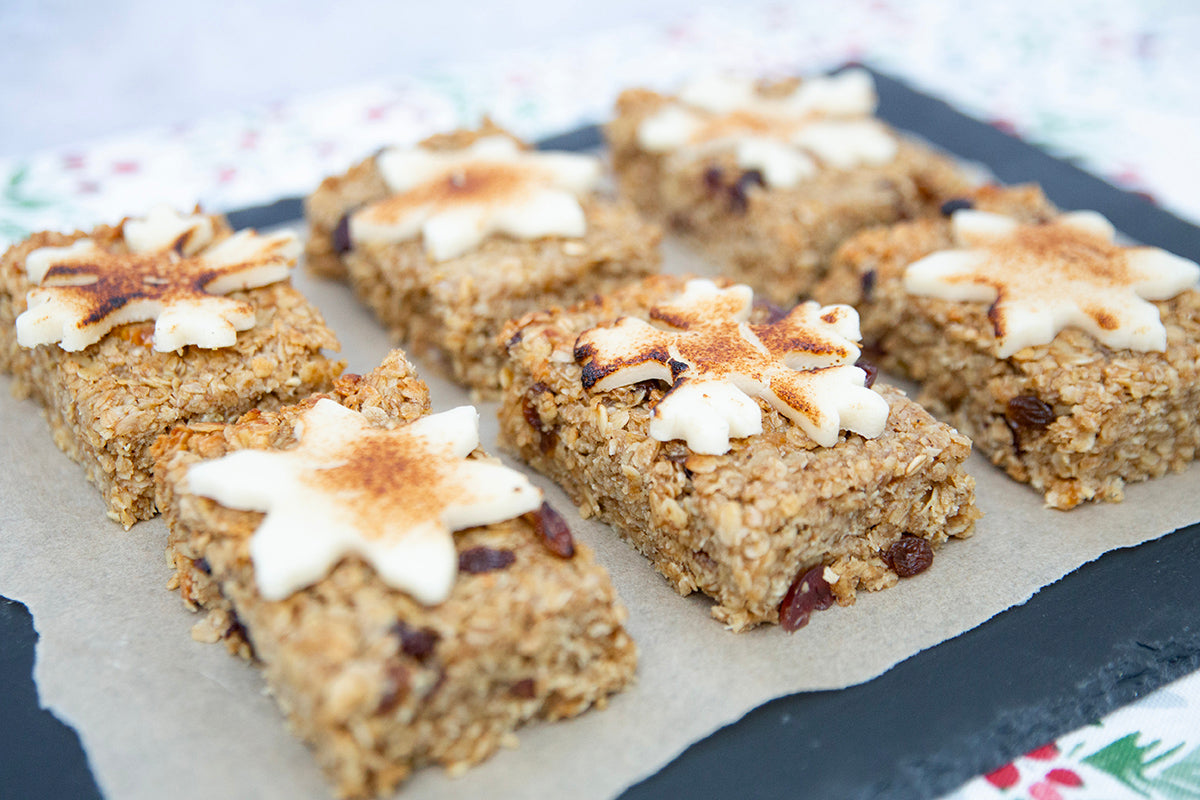  A slice of Christmas flapjack on a white plate, featuring a fruity base and a thick marzipan layer, perfect for the season.
