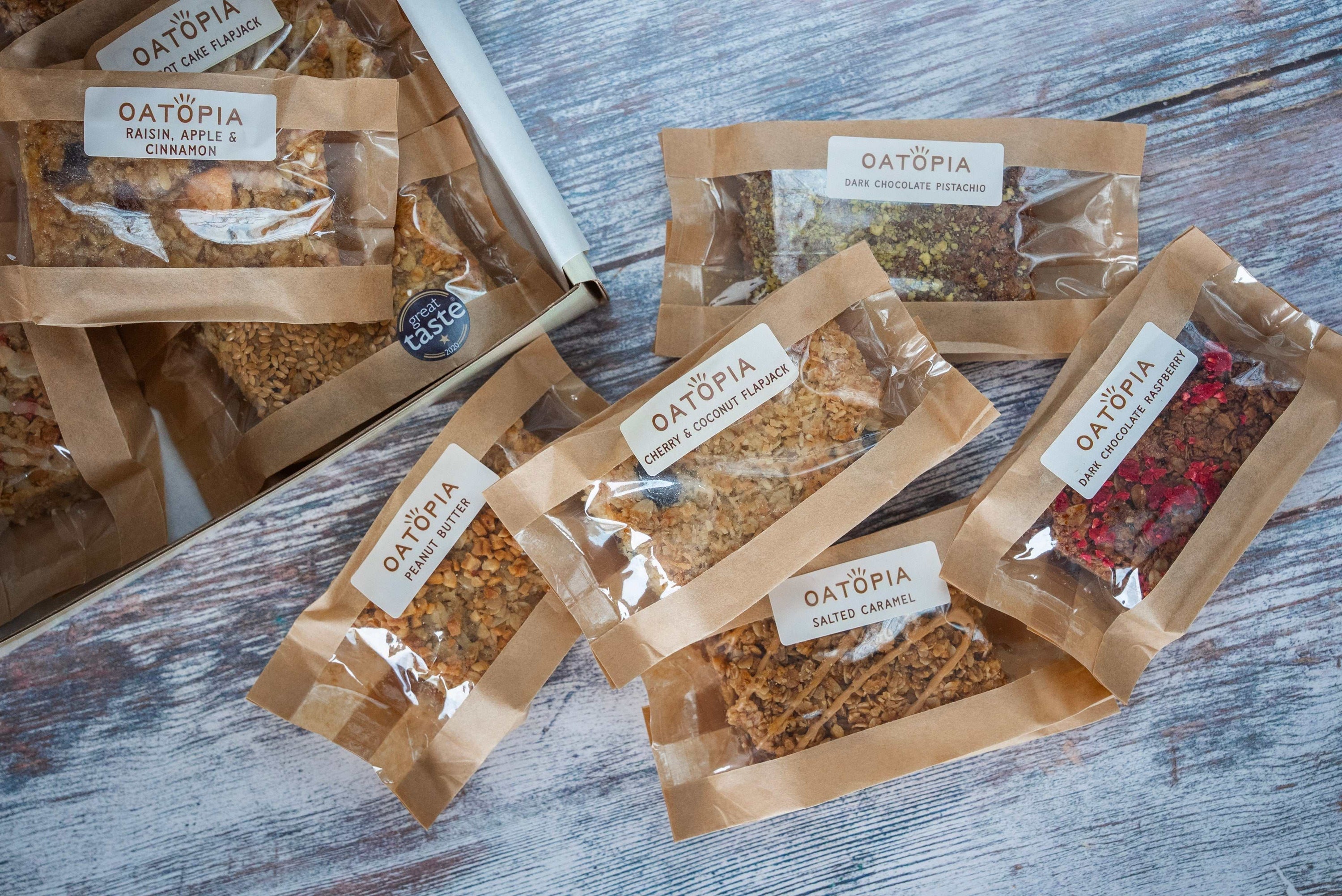 Founder's Favourite vegan flapjack assortment with cherry coconut, dark chocolate pistachio, peanut butter, salted caramel and other oat-based flavours in clear brown packaging on wooden surface