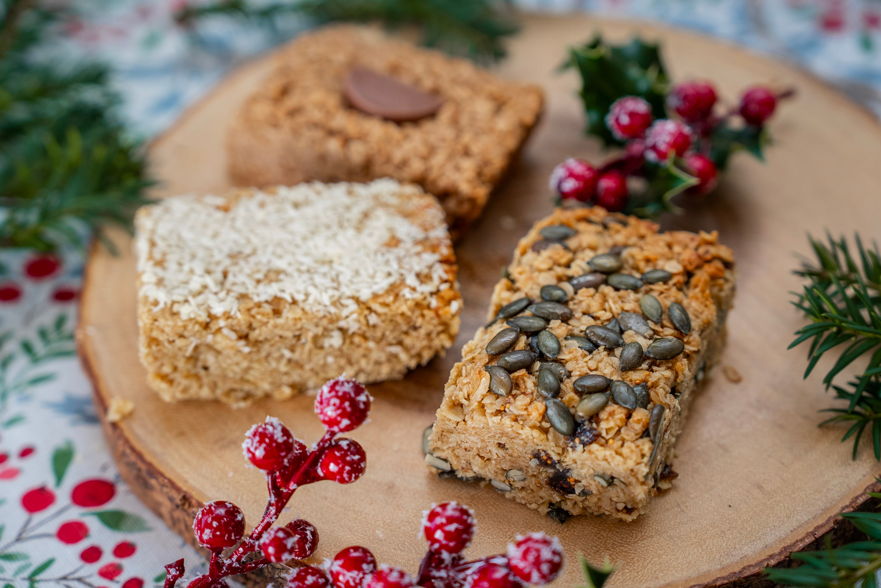 Three flapjack bars on a wooden board with festive decorations
