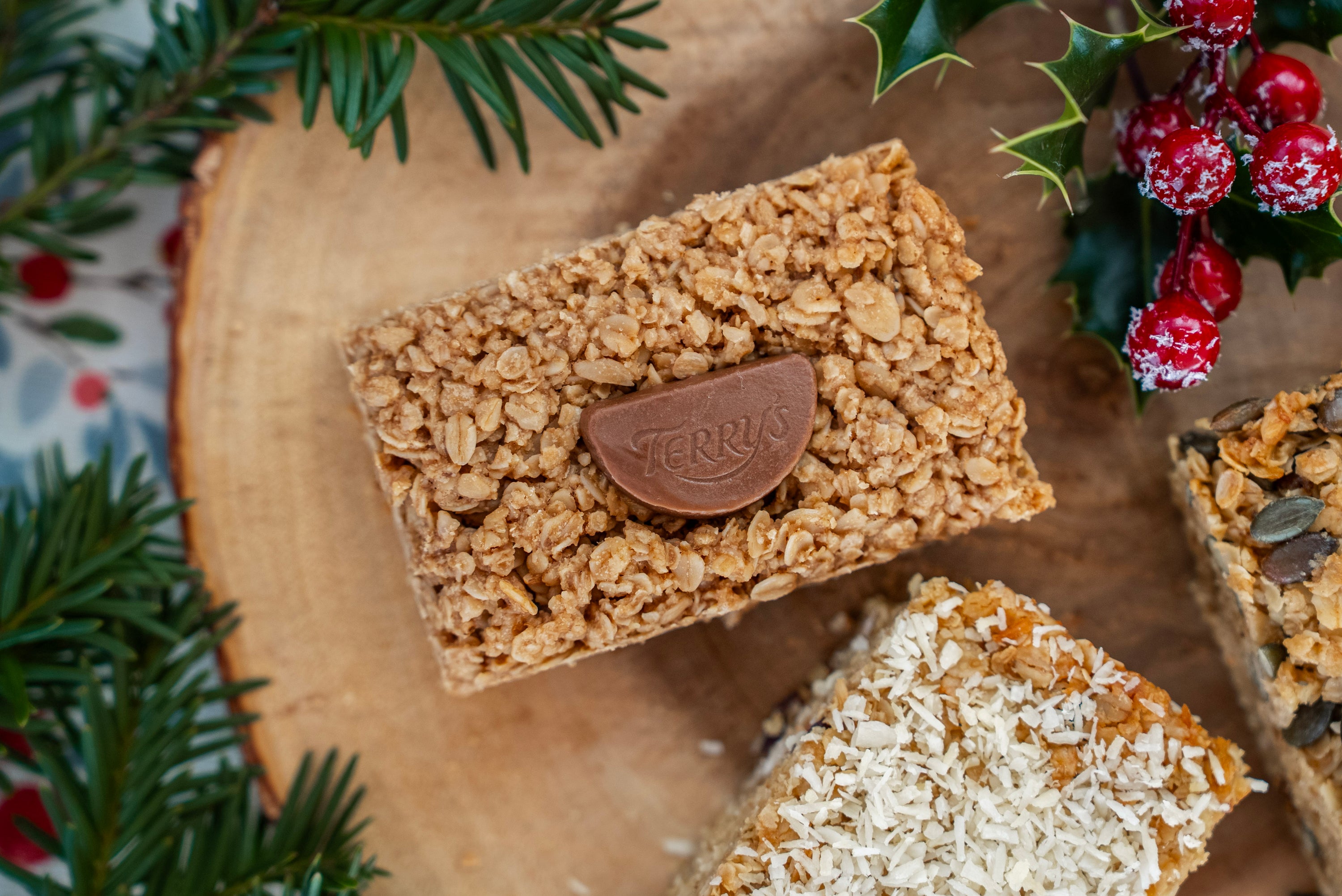 Flapjack bars with a chocolate bar on top, surrounded by Christmas decorations.