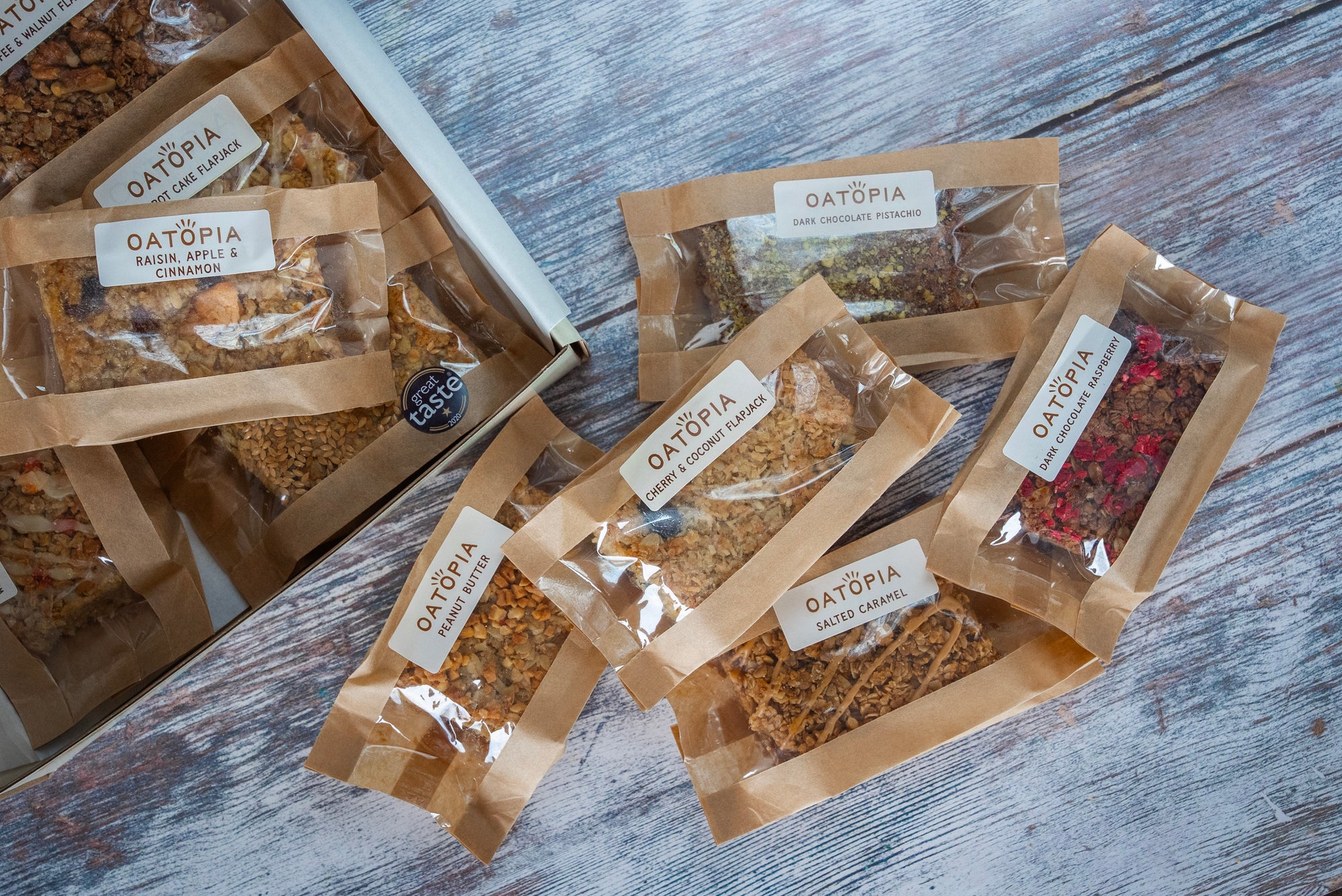 A box of Flapjacks and assorted snacks sits on a rustic wooden table, inviting a healthy snack choice.