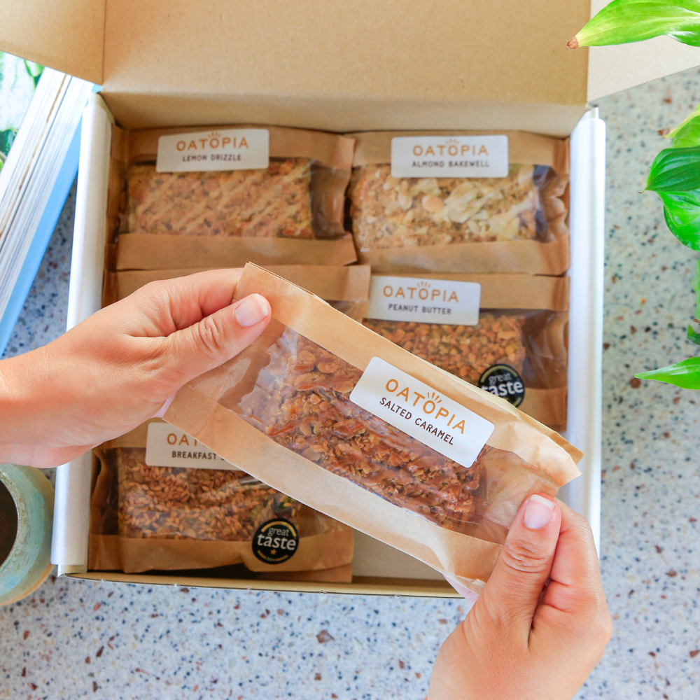 Hands lifting a wrapped Oatopia Salted Caramel flapjack from the Best Seller Flapjack Box.