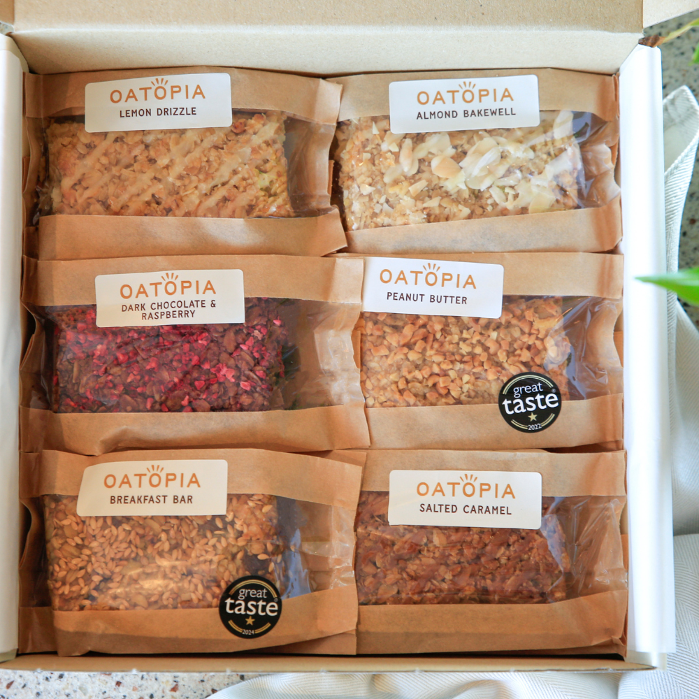 Open Oatopia Best Seller Flapjack Box with six individually wrapped flavours: Lemon Drizzle, Almond Bakewell, Dark Chocolate & Raspberry, Peanut Butter, Breakfast Bar and Salted Caramel.