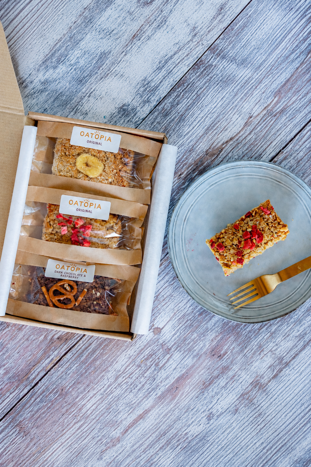 Oatopia Summer Kick Off box featuring a cake, accompanied by a fork and knife for serving.