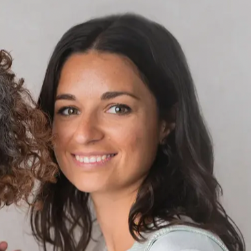 Woman with long dark hair smiling against a neutral background