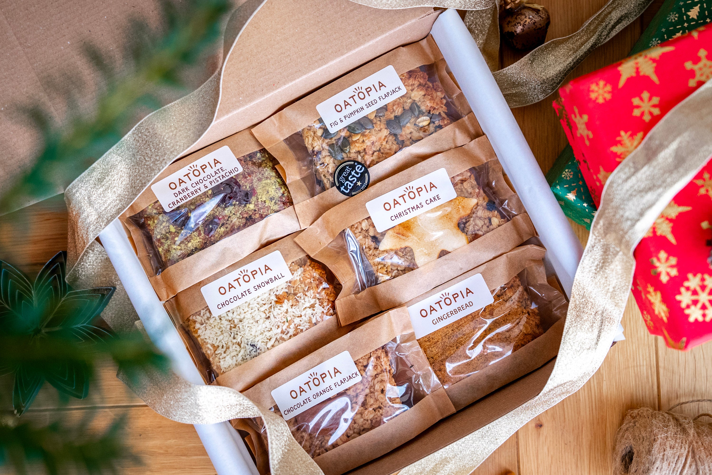 Box of Oatopia flapjacks with a decorative ribbon on a wooden surface.