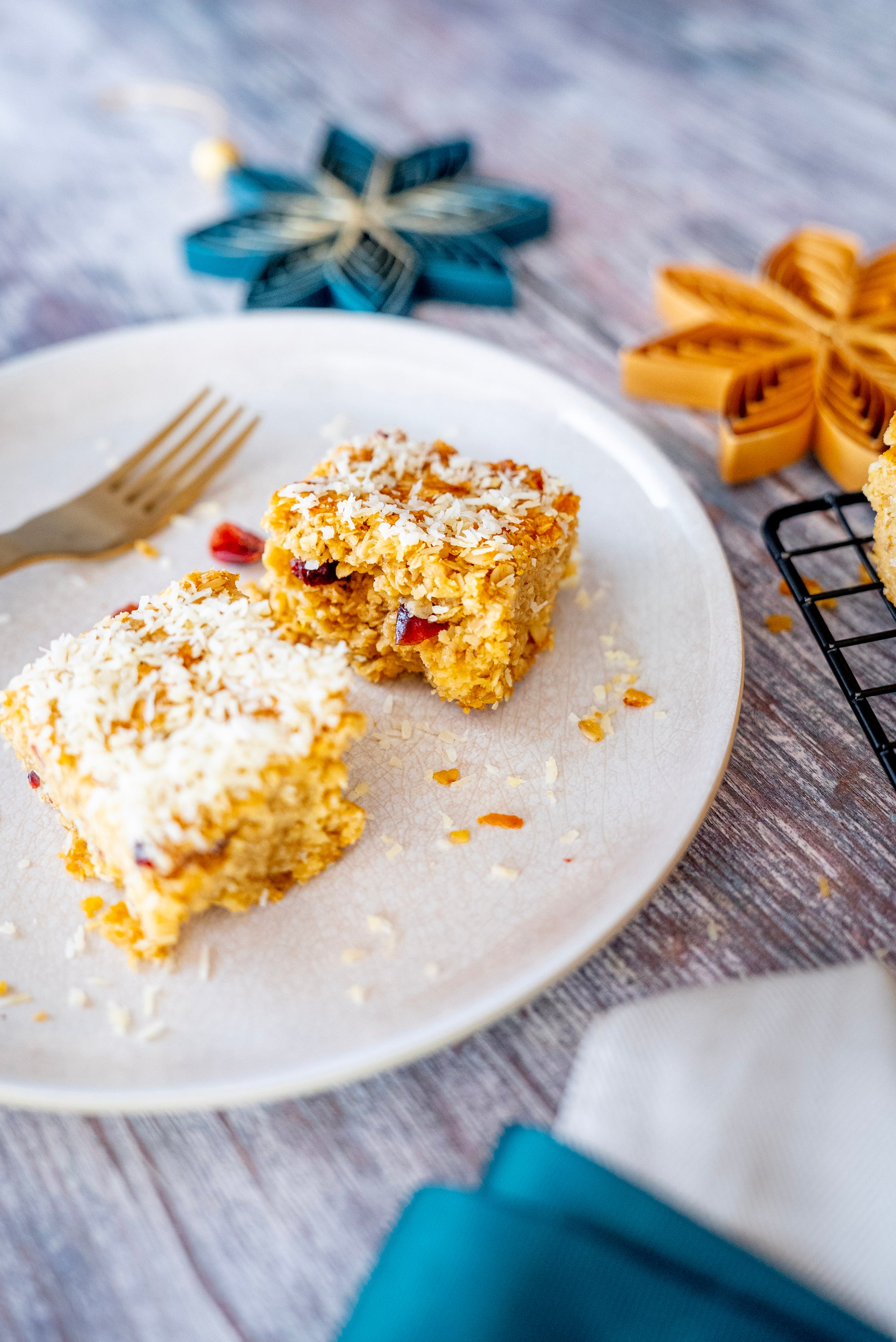 Two pieces of baked dessert on a white plate with a fork, on a wooden surface.