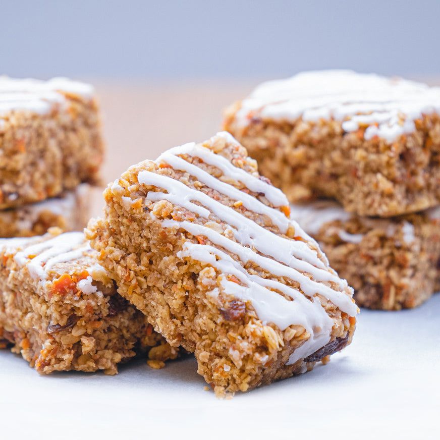 close-up of hand-baked fruit and nut flapjack bars with white drizzle, chewy oats, dried fruit, and nuts, healthy energizing snack